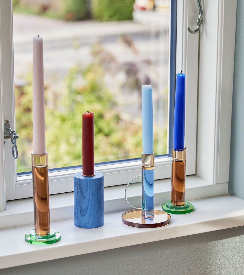 Ensemble de bougeoirs colorés sur un rebord de fenêtre.