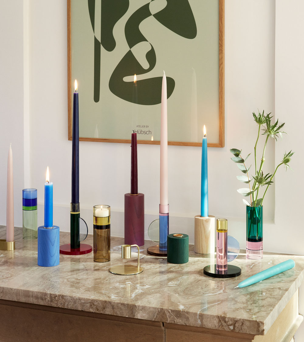 Collection de bougeoirs design, colorés, sur une table.