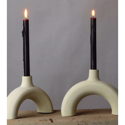 Bougeoir arc en céramique brute avec chandelles noires, style minimaliste.