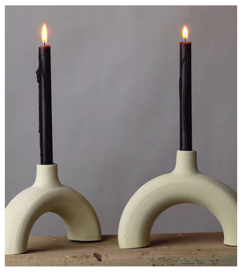 Bougeoir arc en céramique brute avec chandelles noires, style minimaliste.