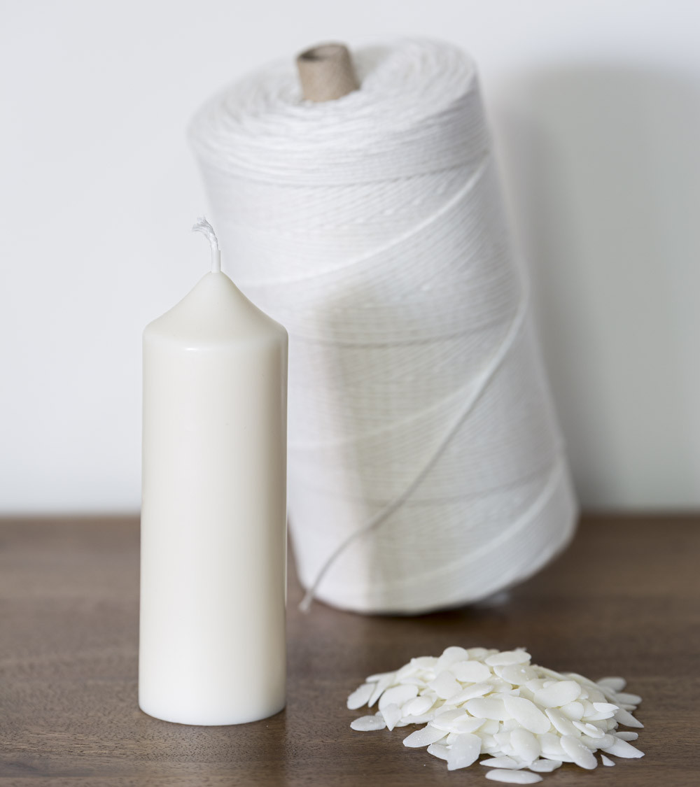 Bougie artisanale en cire de colza Ø 5 cm H 14 cm avec un rouleau de mèche et paillettes de cire de colza sur une table en bois