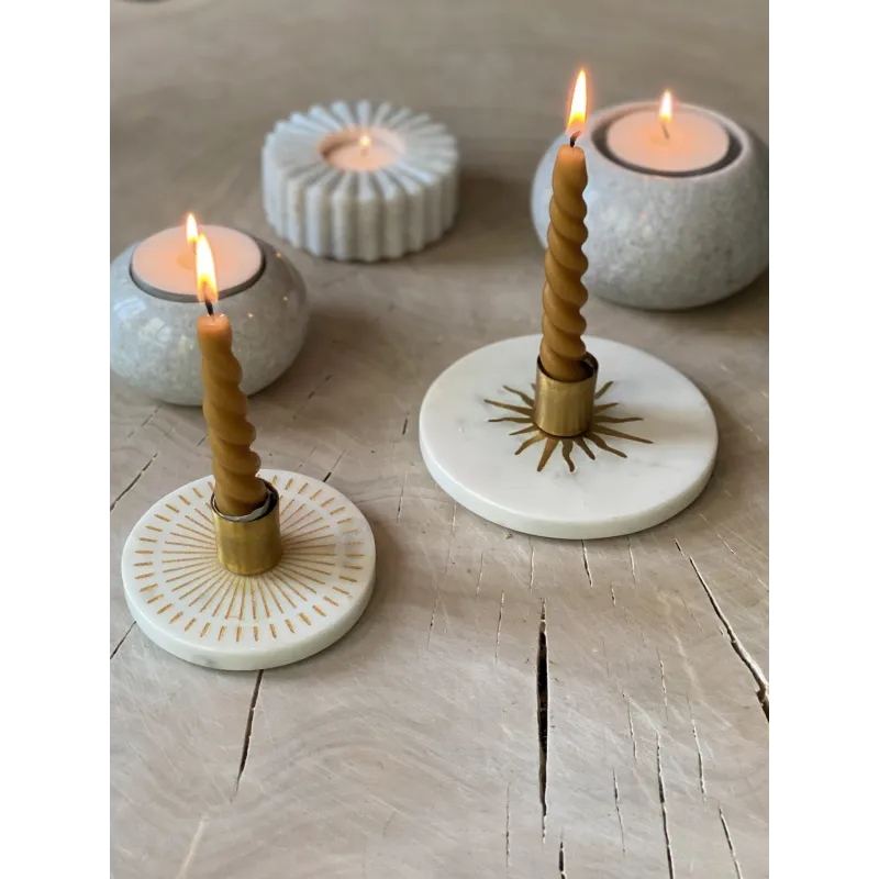 Ambiance chaleureuse avec le bougeoir en marbre L, intégré dans une composition décorative avec d’autres objets en pierre.