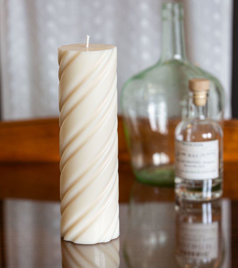 Bougie naturelle et artisanale en cire de colza Ø 7 cm H 23 cm sur une table en verre