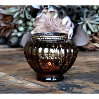 Photophore allumé avec décor floral en arrière-plan.