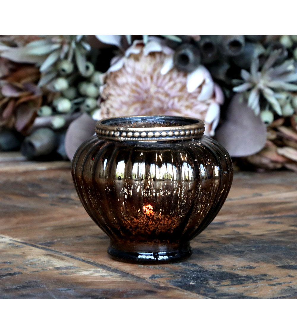 Photophore allumé avec décor floral en arrière-plan.