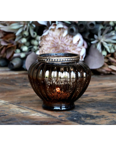 Photophore allumé avec décor floral en arrière-plan.